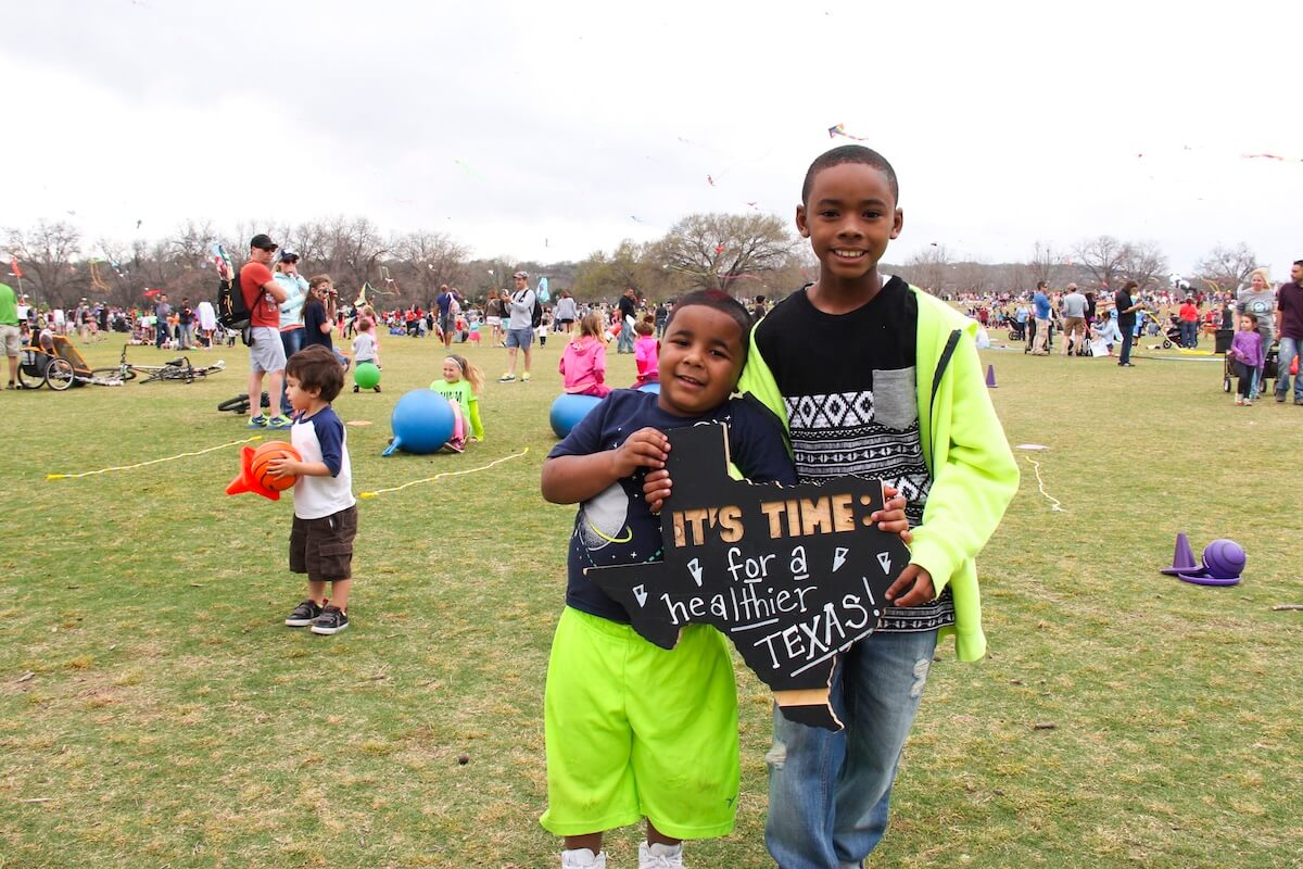 Two boys holding a sign that says It's Time for a Healthier Texas